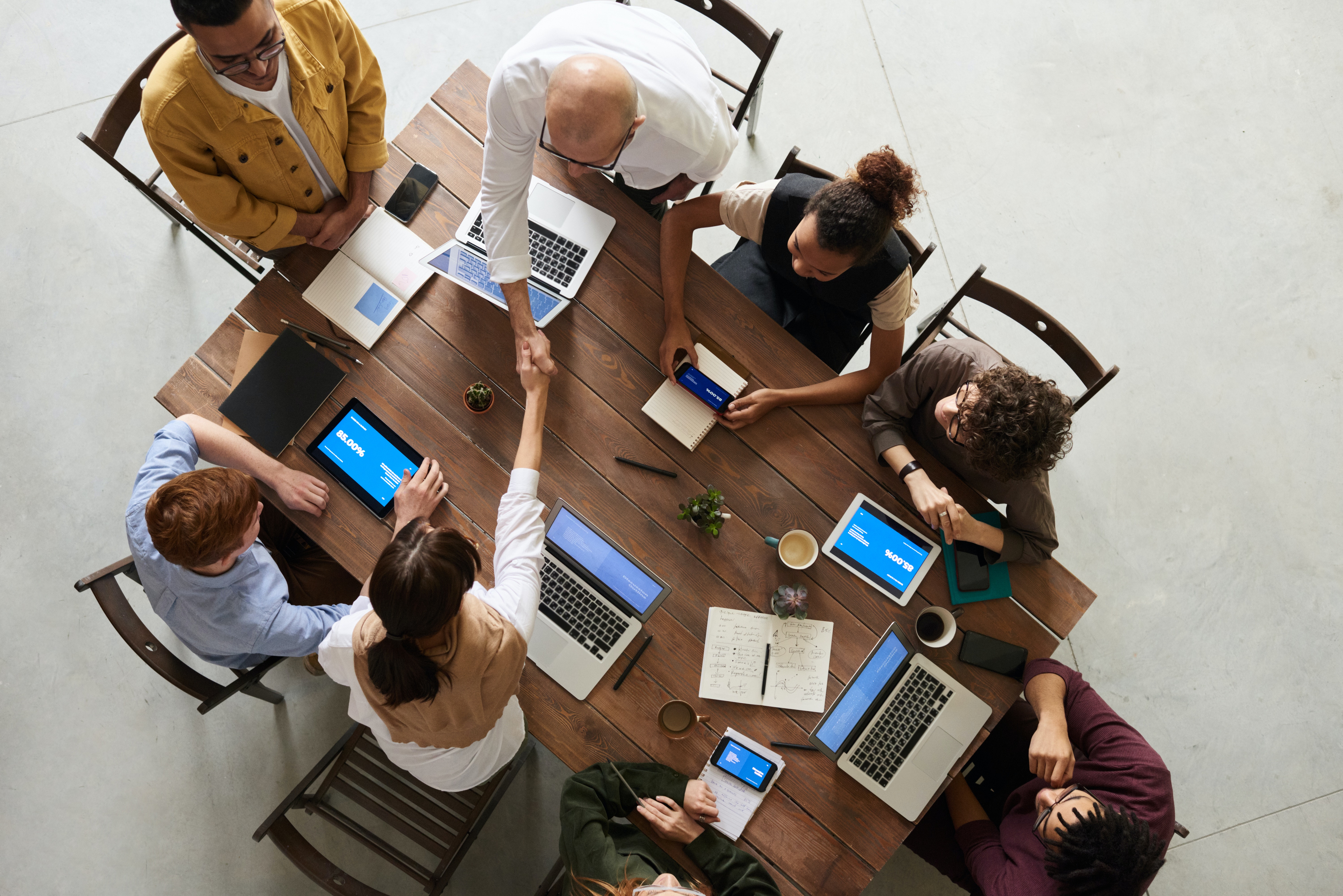 Overhead view of people working at a table, two shaking hands